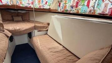 A narrow train compartment with two berths, each with a mattress and a pillow.