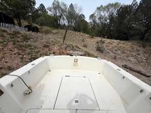 A boat's interior with a central seating area, side steps, and a small hatch. - Rustic Boat Glamping Retreat with Mountain Views near Rio Peñasco in Mayhill, New Mexico (Mayhill)