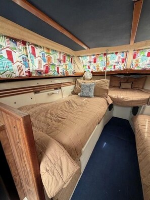 A narrow, enclosed cabin with a bunk bed, a small table, and a patterned wall. - Rustic Boat Glamping Retreat with Mountain Views near Rio Peñasco in Mayhill, New Mexico (Mayhill)