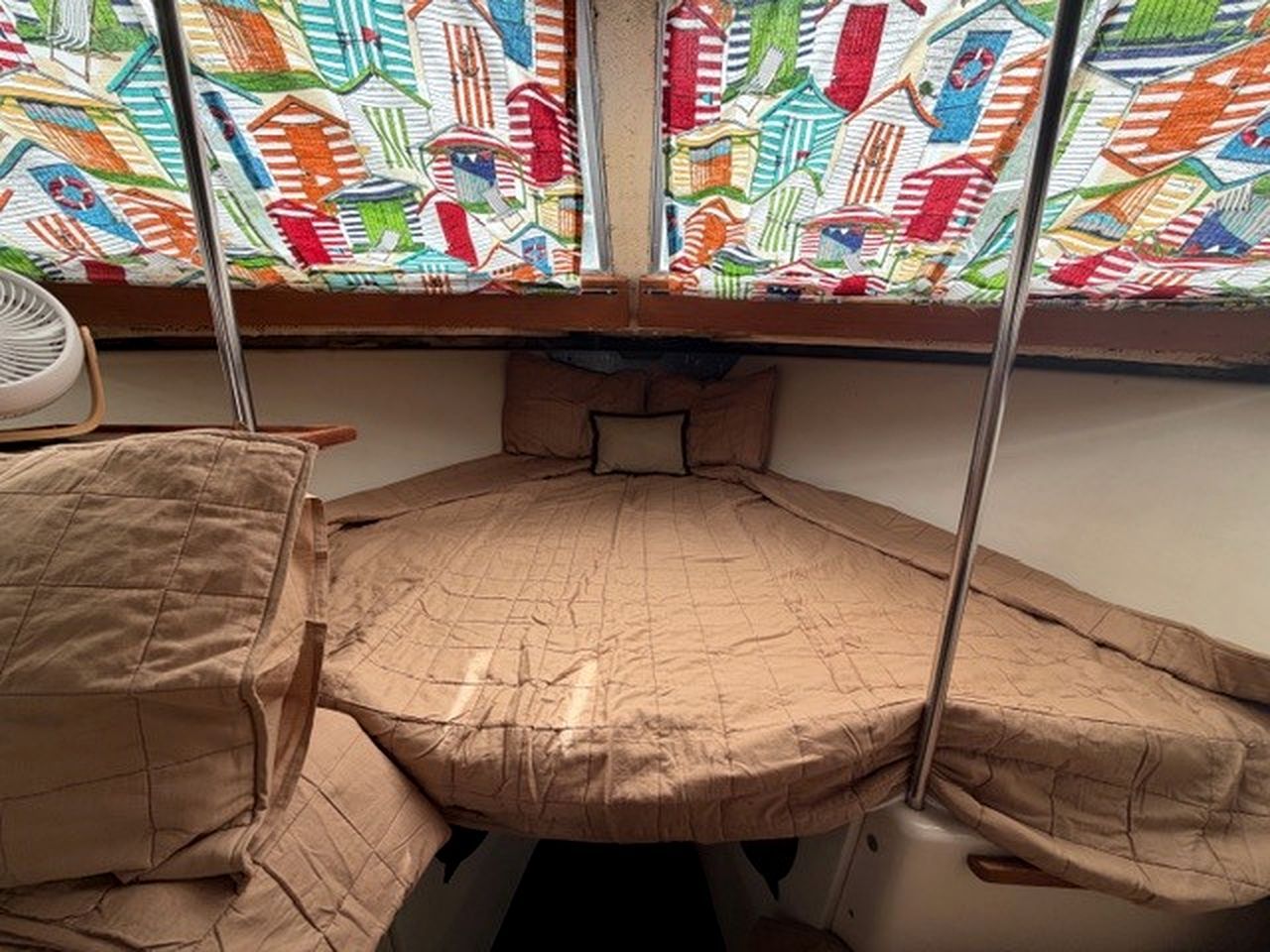 A bunk bed with a quilted mattress, a small table with a chair, and a colorful window with a geometric pattern.
