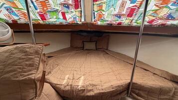 A bunk bed with a quilted mattress, a small table with a chair, and a colorful window with a geometric pattern.