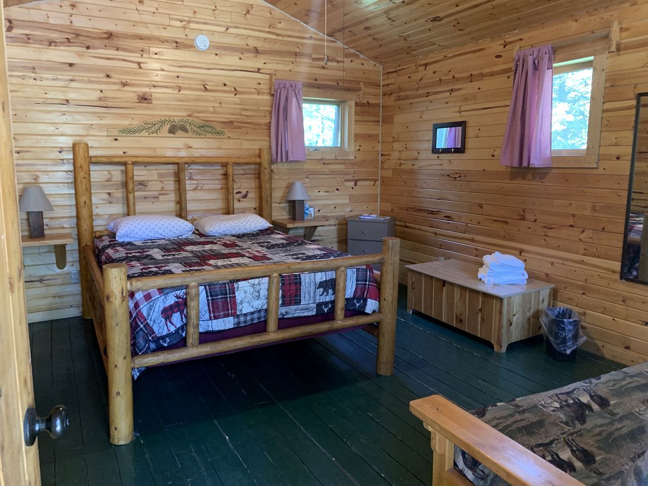 Ein Holzblockhaus-Innenraum mit einem Bett, einer Bank und einem kleinen Tisch.