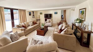 Ein geräumiges Wohnzimmer mit einer großen Couchgarnitur, einem Couchtisch und einem Fernseher.