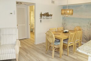 Een eethoek met een houten tafel en stoelen, een armstoel met witte strepen en een aan de muur bevestigde vogelsculptuur.