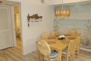 A dining area with a wooden table, wicker chairs, and a wall mural.