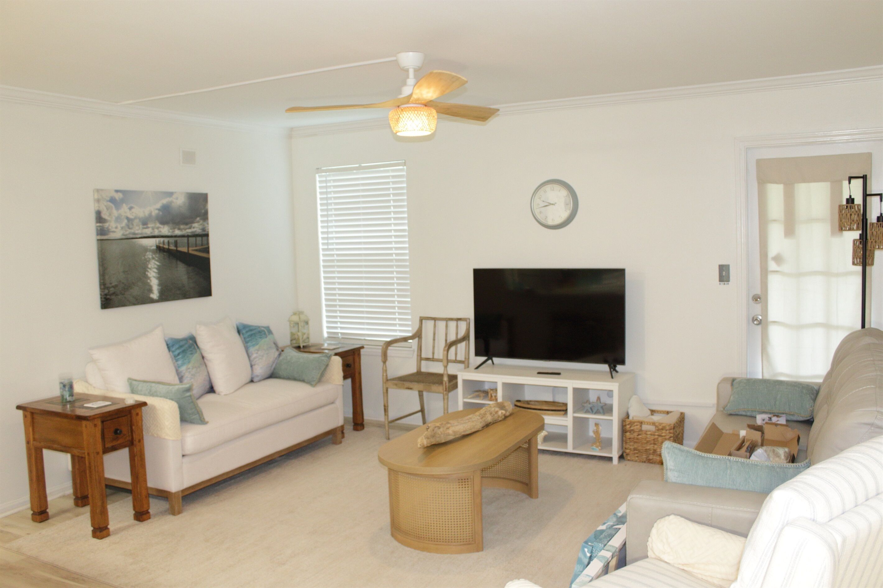 Ein Wohnzimmer mit einer Couch, einem Couchtisch, einem Fernseher und einem Deckenventilator.