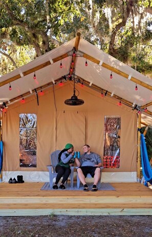 Una tenda con due sedie, una lampada a sospensione e un pontile in legno.