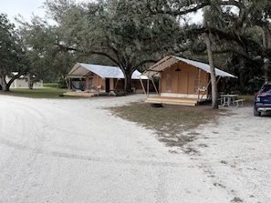 A campsite with two tents, a picnic table, and a car parked nearby.