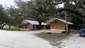A campsite with two tents, a picnic table, and a car parked nearby. - Safari Tent Retreat with Fire Pit and Hammocks in Basinger, Florida (Okeechobee)