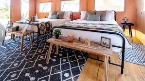 A tent-style room with two beds, a wooden table, and a patterned rug. - Safari Tent Retreat with Fire Pit and Hammocks in Basinger, Florida (Okeechobee)