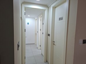 Ein Flur mit Türen, einem Schild mit Toilettenhinweis und einer Deckenleuchte.