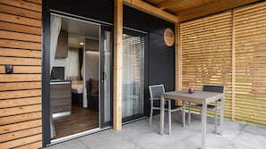 Eine moderne Außenpatio mit Tisch und Stühlen, eine Schiebetür zu einem Raum und ein Holzzaun.
