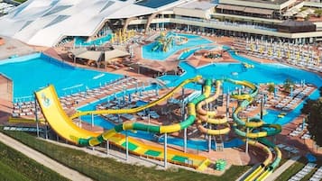 A large water park with multiple slides and pools, surrounded by a covered area with seating.