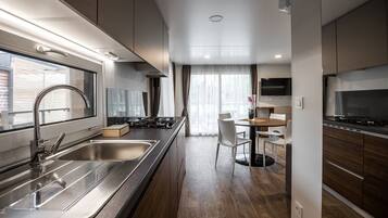 A modern kitchen with stainless steel appliances, a dining area with a table and chairs, and a TV mounted above the counter.