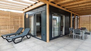 Un'area esterna coperta con tavolo e sedie, una porta scorrevole in vetro e poltrone da relax.
