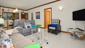 Een woonkamer met een bank, een stoel, een salontafel en een televisie.