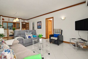 Ein Wohnzimmer mit einer Couch, einem Sessel, einem Couchtisch und einem Fernseher.