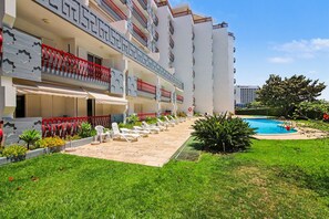 Ein Hotel mit Swimmingpool, Sitzgelegenheiten im Freien und einem gepflegten Garten.