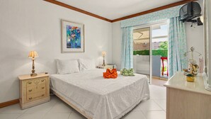 Een slaapkamer met een bed, nachtkastjes, een dressoir, een televisie en een raam met gordijnen.