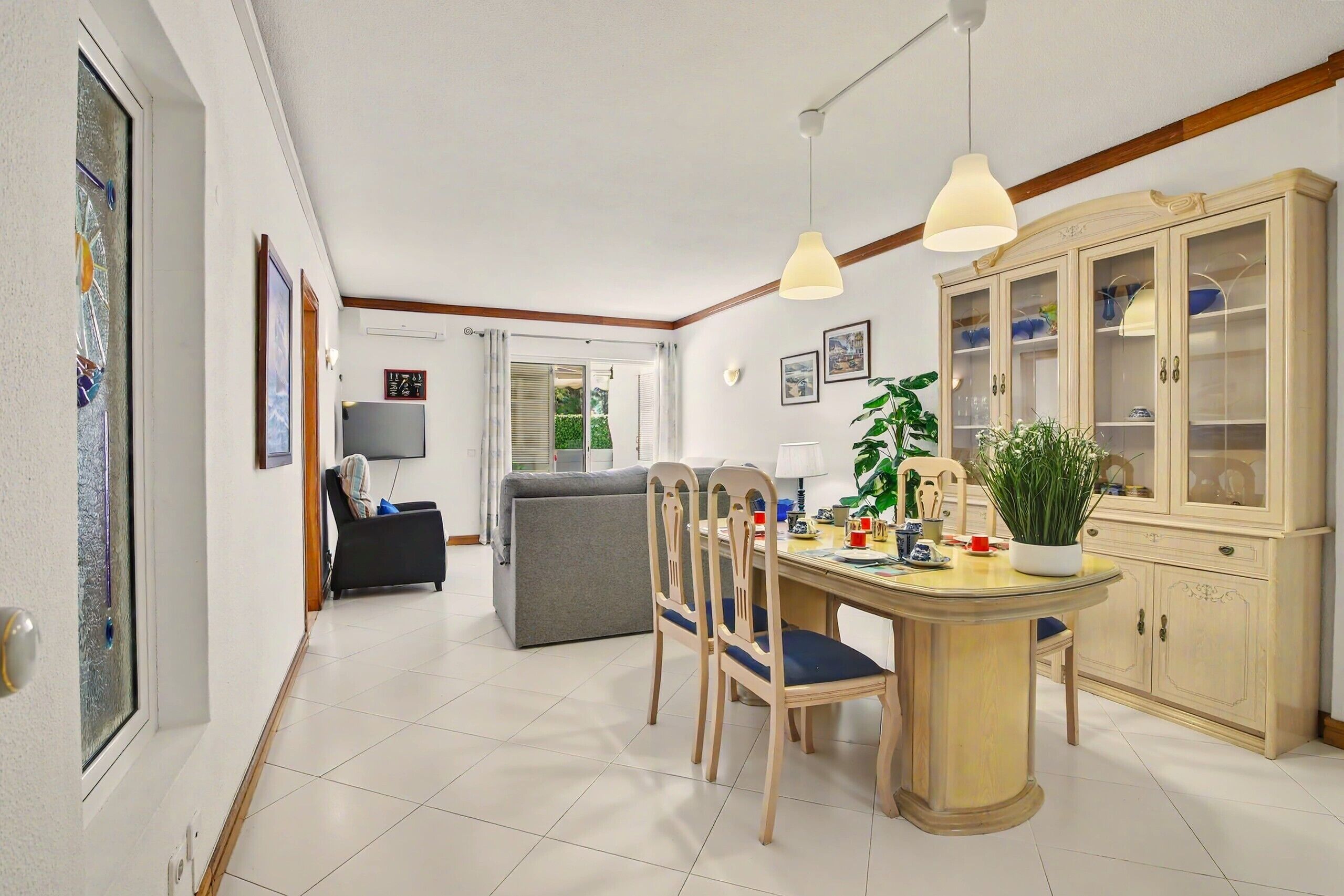 Un espace repas comprenant une table, des chaises, un buffet et une plante.