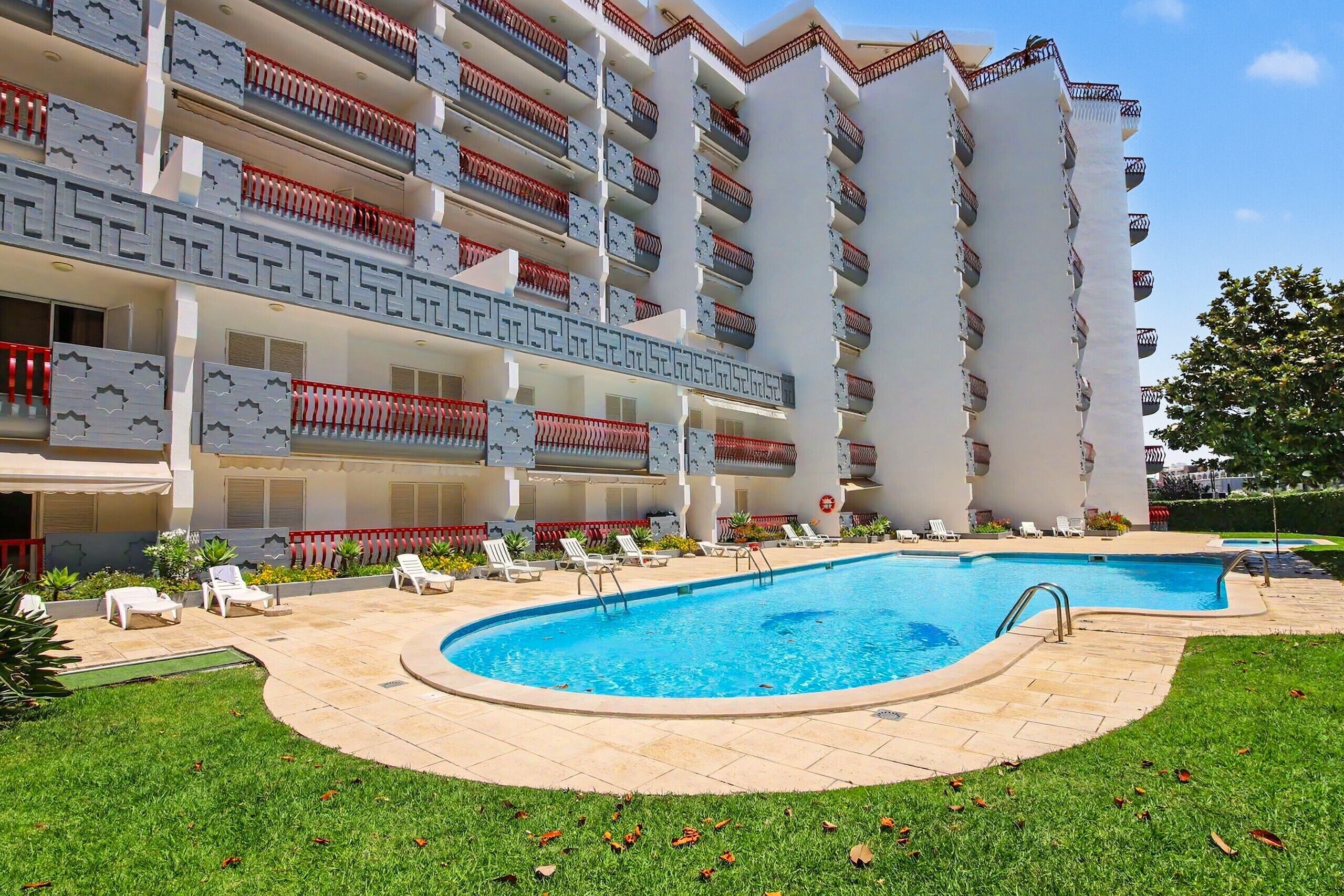 Ein Hotel mit Pool, mehreren Balkonen und einem gepflegten Rasen.