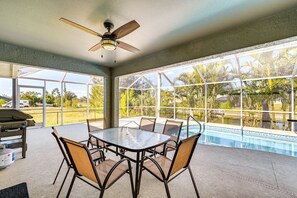 A covered outdoor area with a pool, a table with chairs, and a ceiling fan. - Spacious 4-BR with Patio, Dock + Canal Access (Cape Coral)