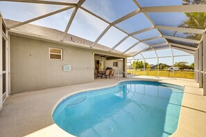 A covered swimming pool with a patio area, a door leading to a building, and a clear sky. - Spacious 4-BR with Patio, Dock + Canal Access (Cape Coral)