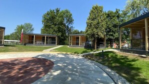 A modern building with a covered outdoor area, a paved walkway, and surrounding greenery. - Terme Tuhelj Glamping Village: Vita Family Mobile Home for 6 People (Tuheljske Toplice)