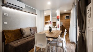 A compact living space with a sofa, dining table, chairs, a kitchen area, and a bathroom. - Terme Tuhelj Glamping Village: Vita Family Mobile Home for 6 People (Tuheljske Toplice)