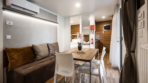 A compact living space with a sofa, dining table, chairs, a kitchen area, and a bathroom. - Terme Tuhelj Glamping Village: Vita Family Mobile Home for 6 People (Tuheljske Toplice)