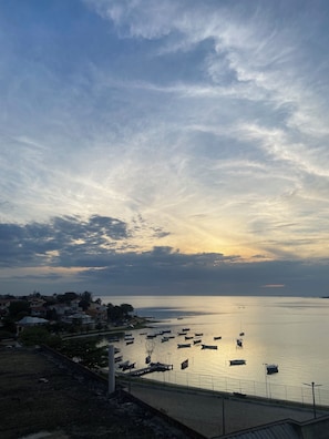 A coastal view with boats docked along the shore, a clear sky, and a calm sea.