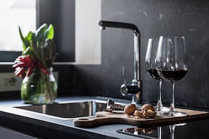 Una encimera de cocina con tabla de cortar, un cascanueces y dos copas de vino tinto.