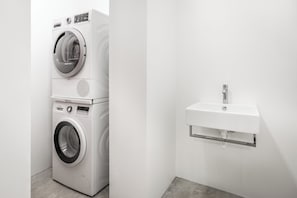 Un área de lavandería moderna con lavadoras apiladas y un lavabo integrado.