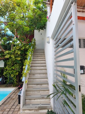 A staircase leading to a door marked with the number 1, surrounded by greenery and a pool. - Charming apartment with a private balcony! (Puerto Morelos)