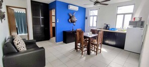 A compact living space with a dining area, kitchenette, and a blue accent wall. - Charming apartment with a private balcony! (Puerto Morelos)