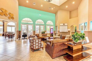 Eine geräumige Lobby mit hoher Decke, großen Fenstern und verschiedenen Sitzbereichen, darunter Sofas und Sessel.