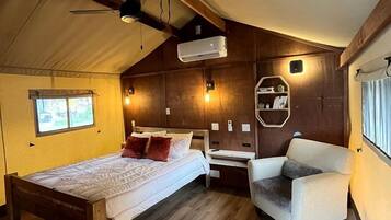 A tent-style room with a bed, a chair, a small table, and a window.
