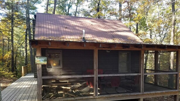 A cabin with a metal roof, a wooden deck, and a large window.