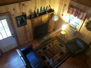 A cozy room with a fireplace, a sofa, a chair, and a rug with animal prints.