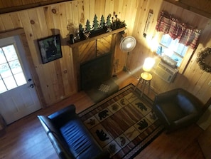 A cozy room with a fireplace, a sofa, a chair, and a rug with animal prints.