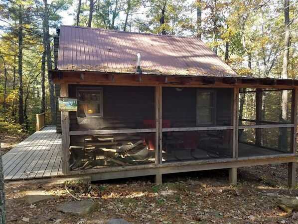 A cabin with a metal roof, a wooden deck, and a large window.