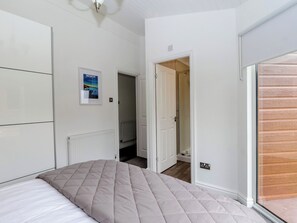 Ein Schlafzimmer mit einem Bett, einem Heizkörper, einer Tür zum Badezimmer und einem Poster an der Wand.