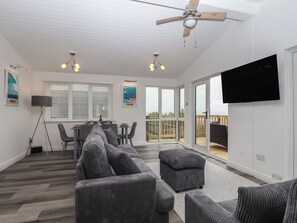 Ein modernes Wohnzimmer mit einem Ecksofa, einem Essbereich und einem Balkon mit Blick.