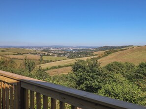 A scenic view from a wooden deck overlooking a town with rolling hills and a clear sky. - Lodge 19 (Torpoint)