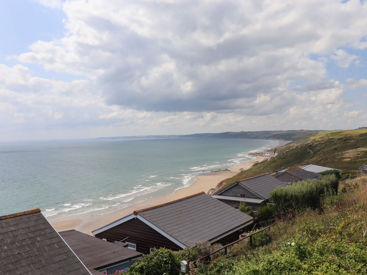 A coastal view with houses overlooking the beach and sea.