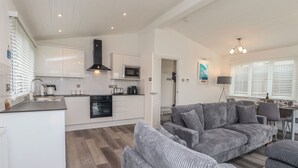 A modern kitchen with white cabinets, a built-in oven, and a microwave. - Lodge 19 (Torpoint)