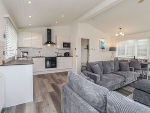 A modern kitchen with white cabinets, a built-in oven, and a microwave. - Lodge 19 (Torpoint)