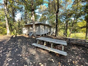 A cabin with a porch, surrounded by trees, and a picnic table in the foreground. - Cozy Waterfront Cabin with Private Pond Views and Outdoor Deck Near Zwolle, Louisiana (Zwolle)