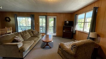 A living room with a sofa, a patterned armchair, a wooden coffee table, and a television.