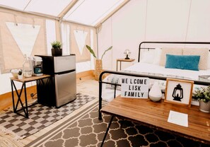 A cozy room with a bed, a small table with a welcome sign, a refrigerator, and a coffee maker. - Incredible Tented Cabin with Stunning Forest Views in Sarasota, Florida (Sarasota)